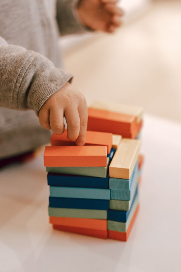 A child arranging colorful wooden blocks in a vertical stack during playtime indoors.